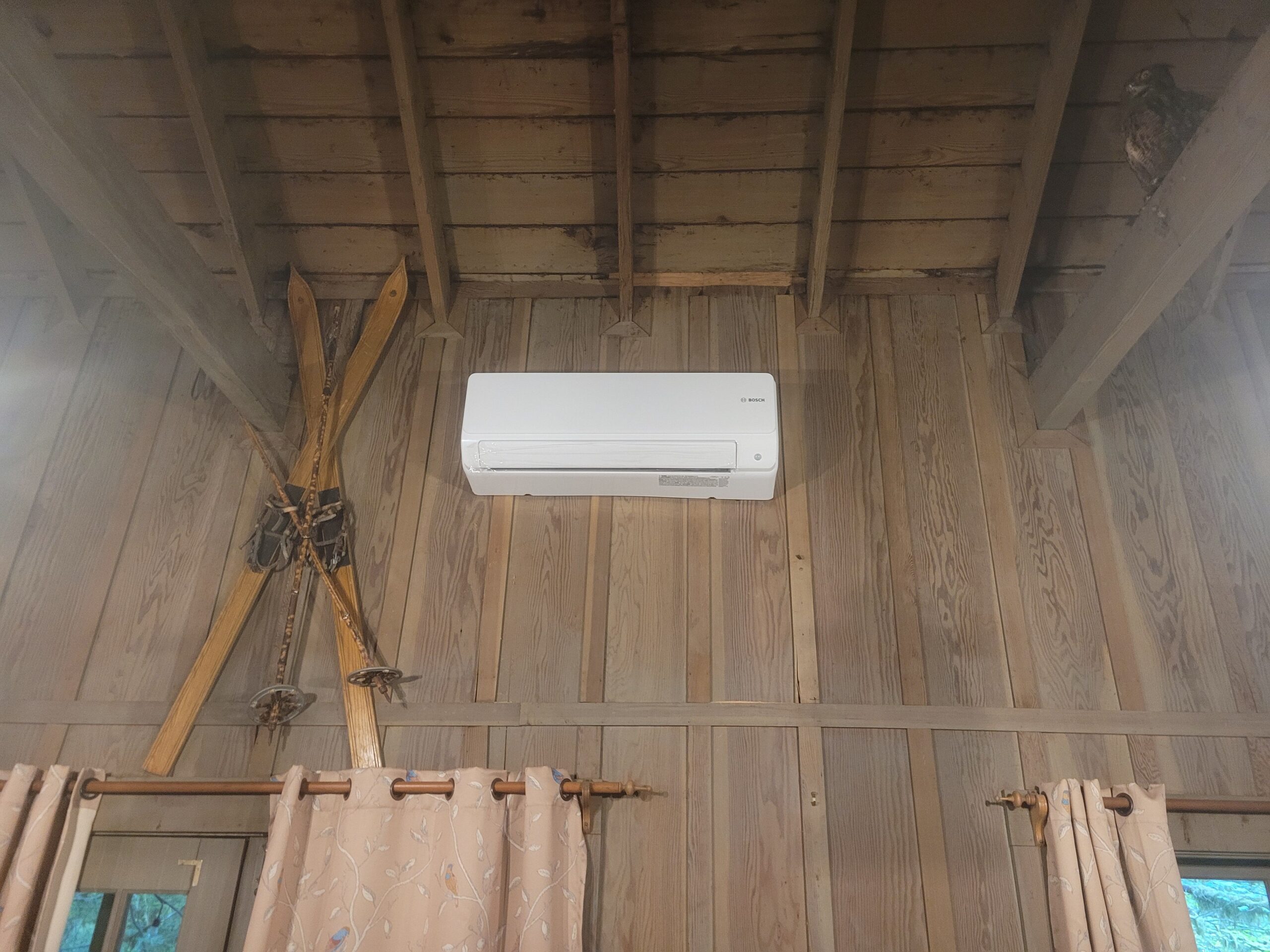Bosch ductless mini-split indoor unit mounted high on a wooden cabin wall with exposed beam ceiling