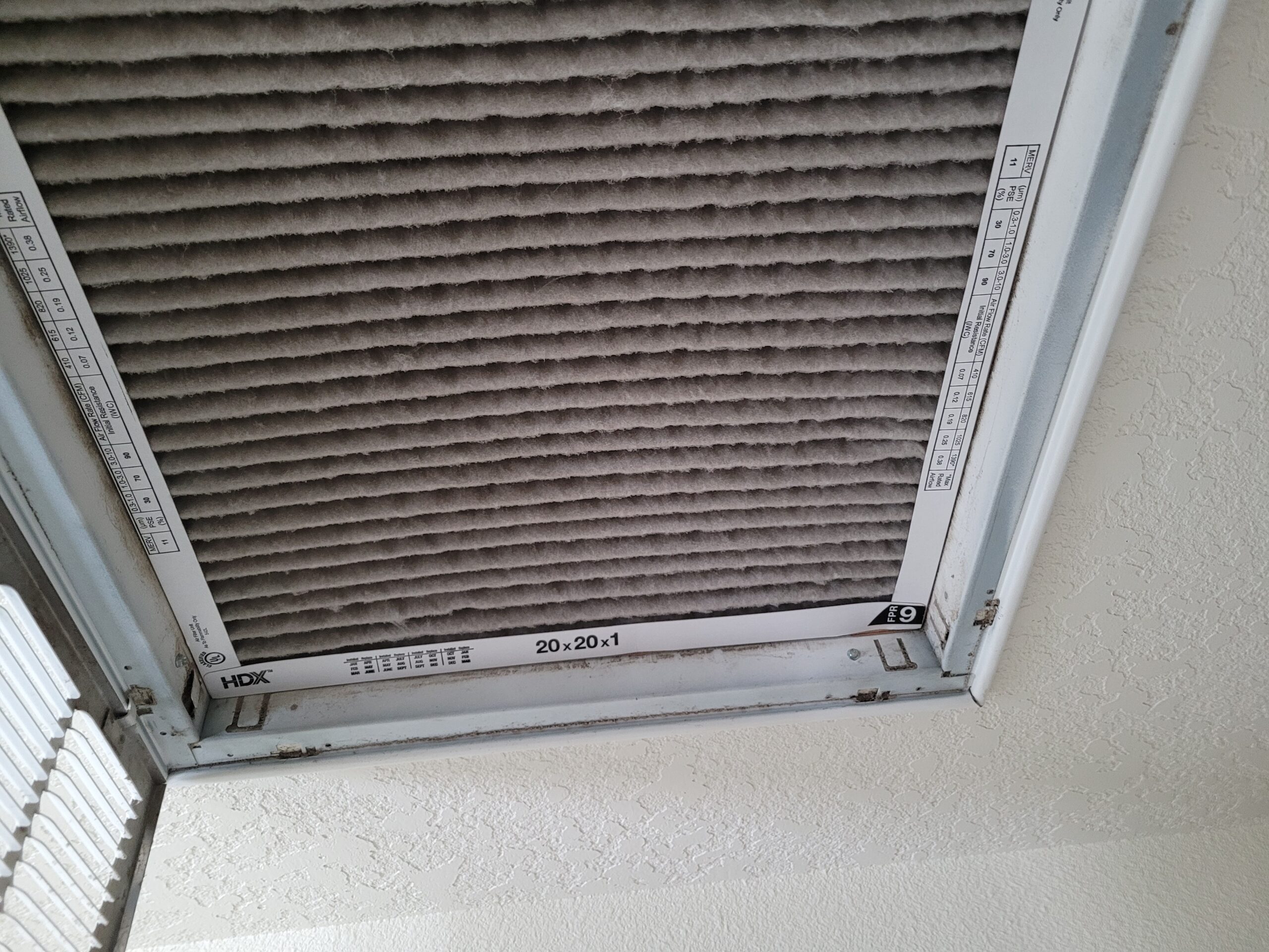 Dirty 20x20x1 HVAC air filter in a ceiling return vent, overdue for replacement