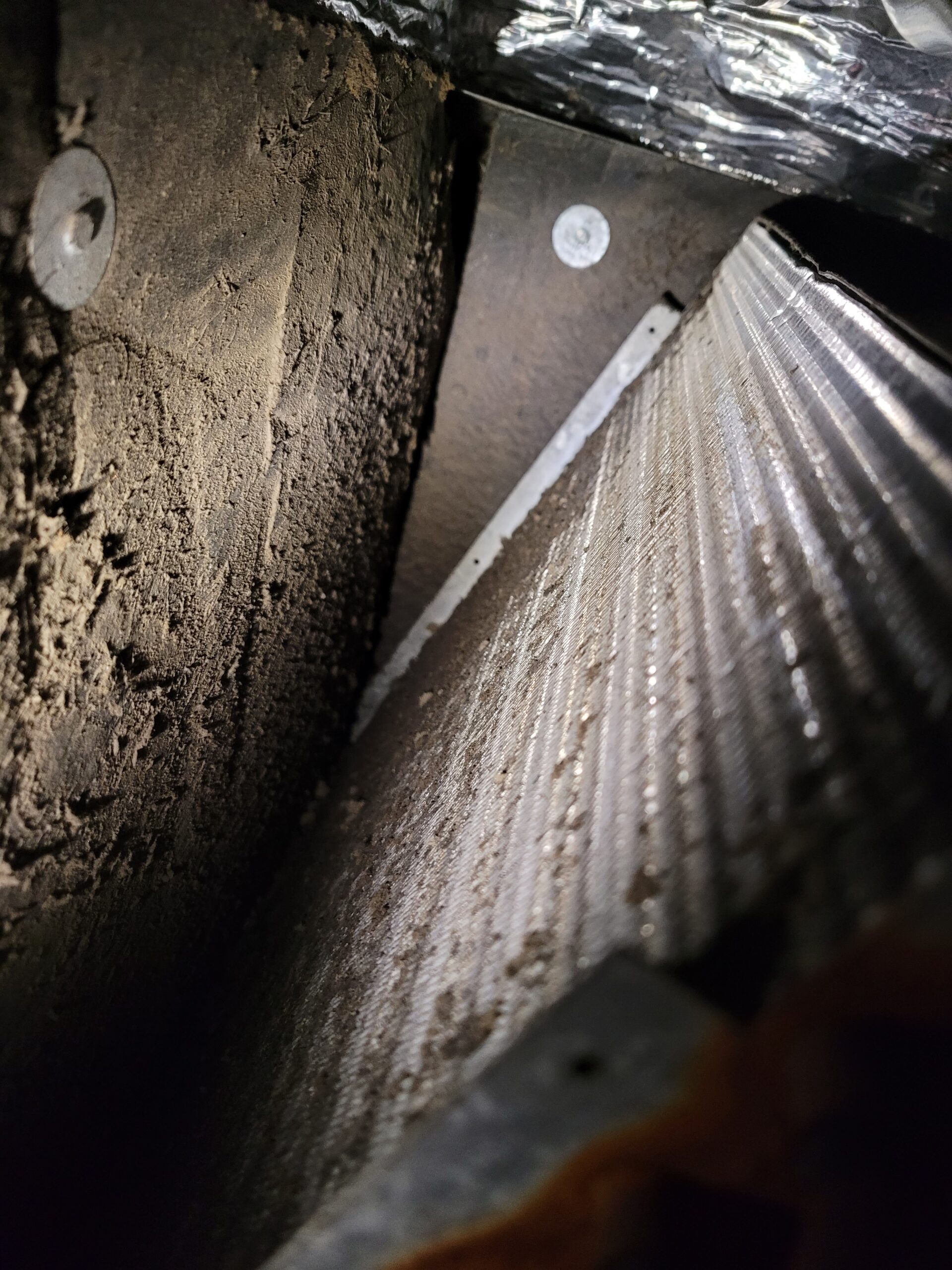Dust-and-debris-coated evaporator coil and plenum interior of an HVAC system in need of cleaning
