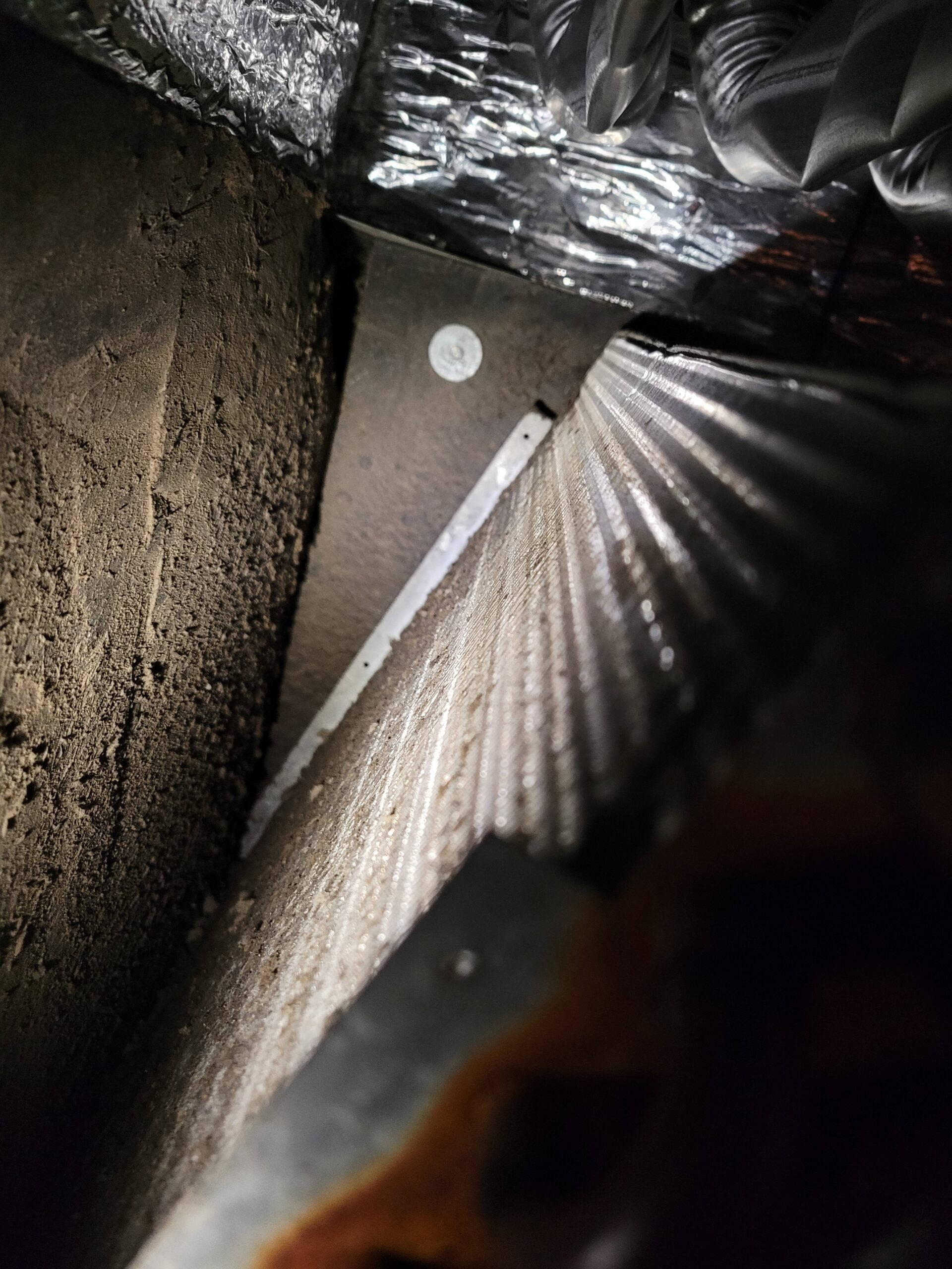 Dusty flexible duct connection to a metal plenum showing debris accumulated around the joint