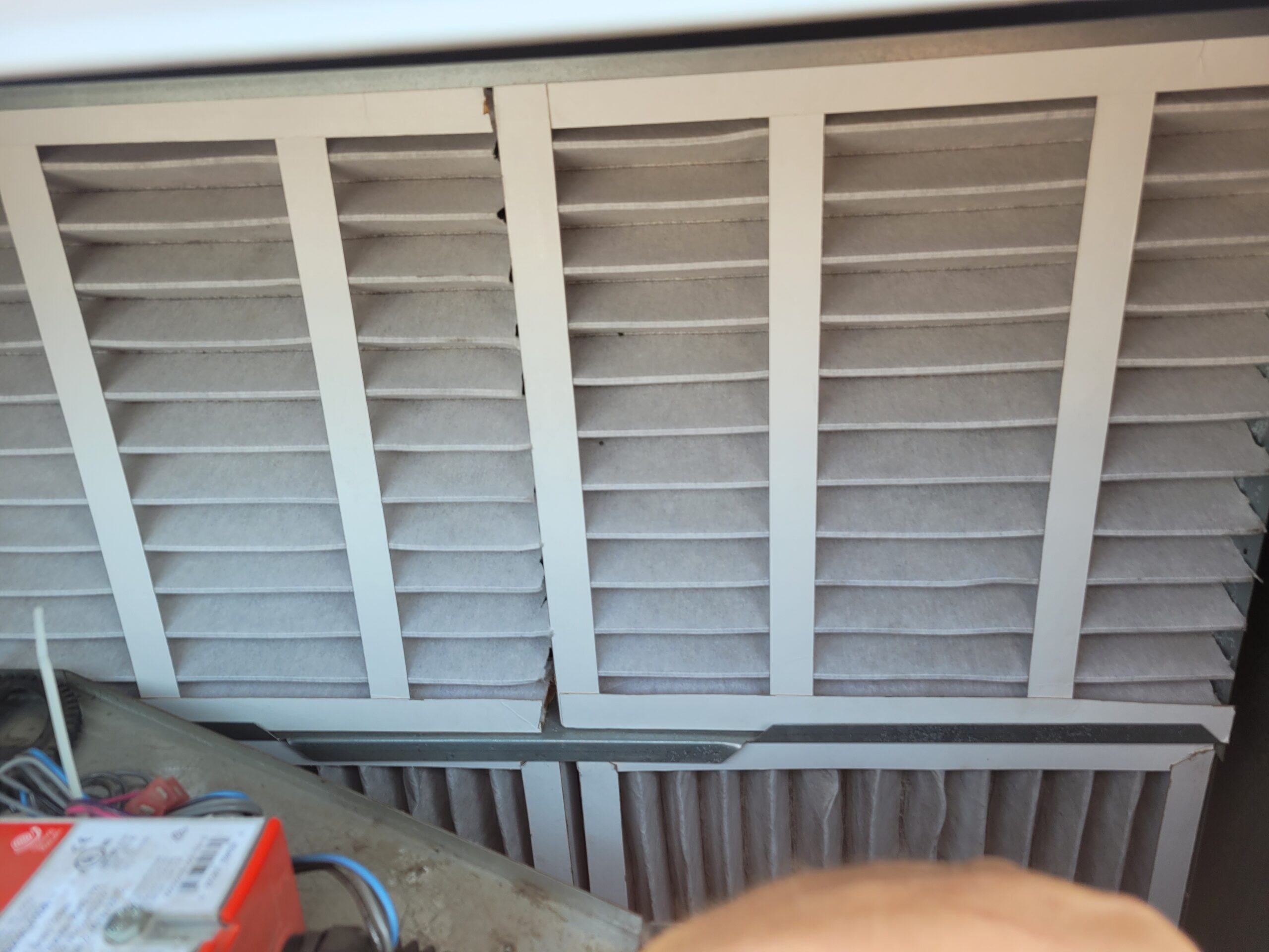 Pleated HVAC air filters installed in an air handler unit with visible dust accumulation