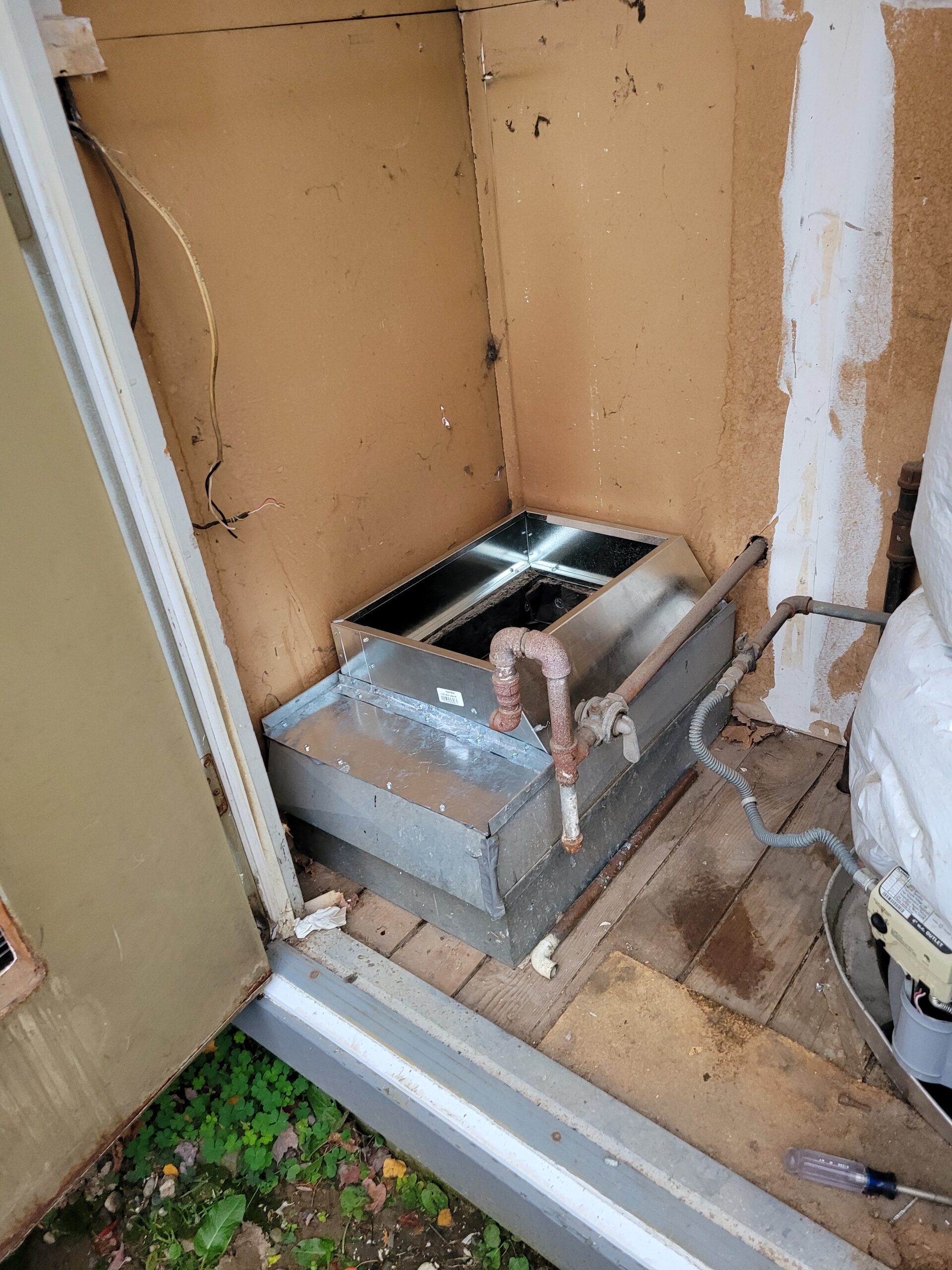 Evaporator coil and copper refrigerant lines installed in a utility closet near an exterior wall