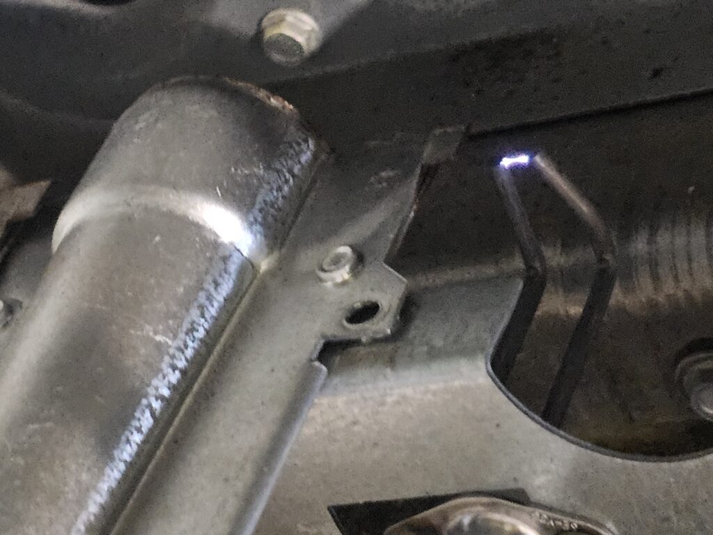 Close-up of a furnace burner tube beside a bent spark igniter electrode with a small blue spark arcing at its tip