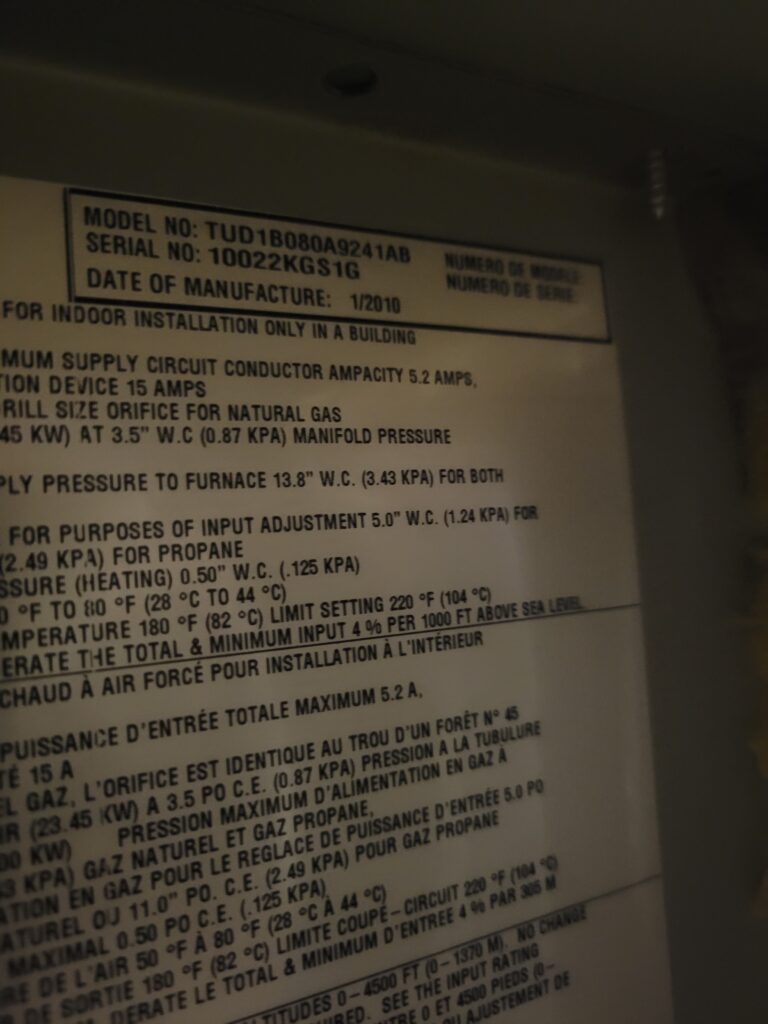 Close-up of a furnace rating plate showing model TUD1B080A9241AB, serial number, January 2010 manufacture date, and gas specs